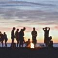 Jóvenes en grupo en torno a un fuego en la playa al atardecer